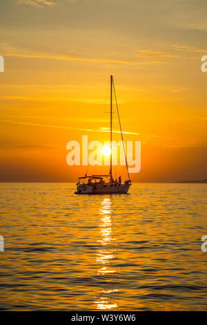 Bateau à voile au coucher du soleil, la ville de Mykonos, Mykonos, Cyclades, Grèce Banque D'Images