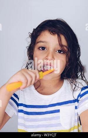 Portrait vertical d'une petite fille se brosser les dents dans la salle de bain le matin après la douche, pour les enfants, copie espace concept d'hygiène pour le texte Banque D'Images