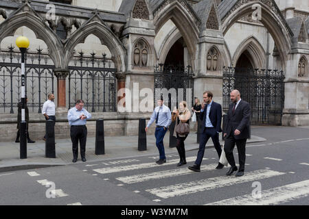 Des collègues de travail à pied le long de la rue de la flotte alors que la route est bloquée par des manifestants à l'extérieur, la rébellion d'extinction la Royal Courts of Justice (La Haute Cour) sur Fleet Street, le 15 juillet 2019, à Londres, en Angleterre. Banque D'Images