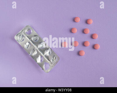 Distributeur de pilules utilisées, pilule suivante sur fond violet Banque D'Images