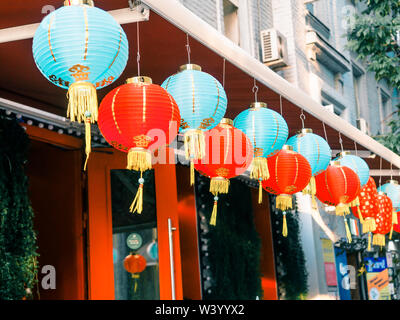 Lanternes de papier chinois sur l'oscillation de vent sur le toit d'un bâtiment par jour dans la rue Banque D'Images