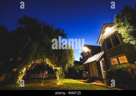 Photo à angle bas d'une arrière-cour avec des feux d'arbre suspendus la nuit près de la maison dans le comté de Sonoma, CA Banque D'Images