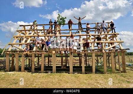 Une nouvelle reproduction médiévale Anglo saxon traditionnel bâtiment en chêne avec les gens qui aident à construire à ce stade Banque D'Images