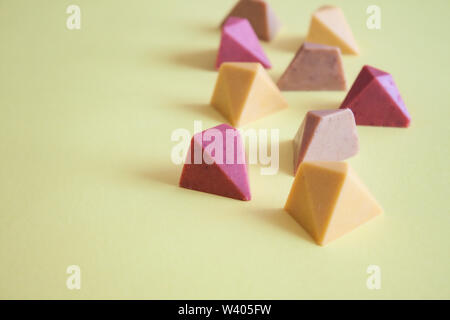 Chocolat pralines vegan colorés sur fond jaune. Banque D'Images