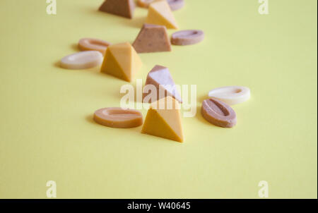 Chocolat pralines vegan colorés sur fond jaune. Banque D'Images