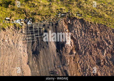 Construction de barrières de protection contre les chutes de roches et les glissements de terrain dans la province montagneuse. Les travailleurs renforcent la pente de la montagne avec une grille métallique. Banque D'Images