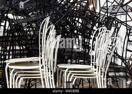 Bucarest, Roumanie - 01 juillet 2019 : beaucoup de blanc ou noir, chaises en fer forgé sont stockés les uns sur les autres dans une rue de Bucarest. Cette image est pour Banque D'Images