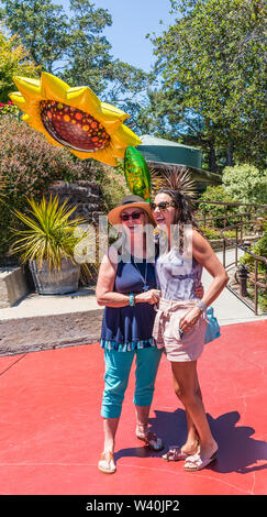 Deux femmes de la génération y célébrer l'un de leurs anniversaires avec un énorme ballon mylar en forme de soleil sur le patio au Nepenthe restaurant sur la route 1. Banque D'Images