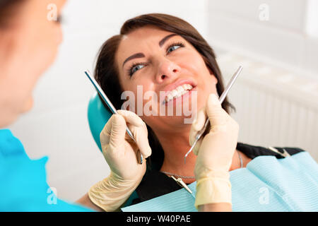 Mettre appareil dentaire pour les dents de la femme au cabinet dentaire. Dentiste examiner female patient with braces en cabinet dentaire. Close-up of a young Banque D'Images
