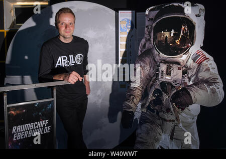 Eberswalde, Allemagne. 17 juillet, 2019. Benjamin Stöwe, propriétaire de Star Trek le musée "paceship Eberswalde', se tient à côté d'un écran d'une photo de l'astronaute américain Edwin "Buzz" Aldrin entrant dans la lune. Dans la cave d'un immeuble à appartements à Eberswalde, l'infinie immensité de l'espace commence. 'Benjamin' Trekkie Stöwe a mis en place un musée unique 'Star Trek'. Pour un jour tout ce qu'il y tourne autour de l'alunissage, il y a 50 ans. (Dpa 'l'alunissage dans la 'spaceship Eberswalde'') Credit : Patrick Pleul/dpa-Zentralbild/ZB/dpa/Alamy Live News Banque D'Images