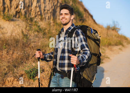 Smiling attractive young man carrying backpack, randonnées Banque D'Images
