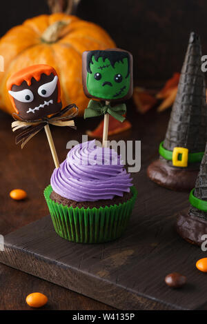 Halloween fête sweet treats - cupcake et cake pops ou guimauve au chocolat Monstres et sorcières wafer de chapeaux. Fond de bois foncé, selectiv Banque D'Images