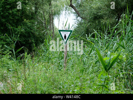 Berlin, Allemagne. 16 juillet, 2019. Un panneau avec l'inscription 'Naturschutzgebiet dans den Niedermoorwiesen suis Tegeler Fließ' près de Lübars dans le quartier de Reinickendorf. Le paysage de l'Tegeler Fließtales est caractérisée par des lits de roseaux, lacs, prairies humides, forêts d'aulnes et les plans d'eau. Sur les zones plus élevées, les prairies et les pâturages ainsi que les haies et les plantations fruitières anciennes diverses font partie de la réserve naturelle. Credit : Jens Kalaene Zentralbild-/dpa/ZB/dpa/Alamy Live News Banque D'Images