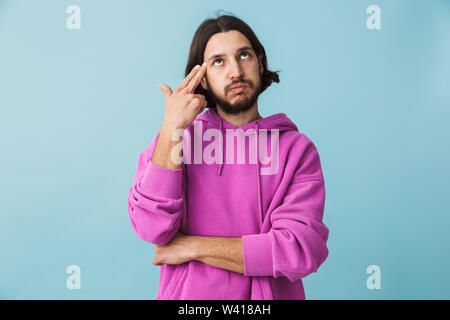 Portrait d'une jeune brunette barbu homme portant hoodie isolés sur fond bleu Banque D'Images