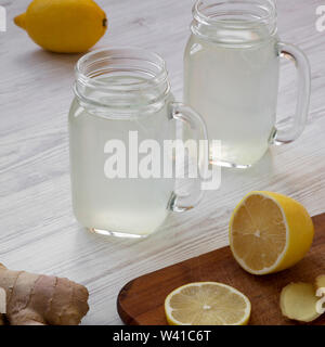 Thé au citron gingembre maison dans des bocaux en verre blanc sur fond de bois, low angle view. Close-up. Banque D'Images