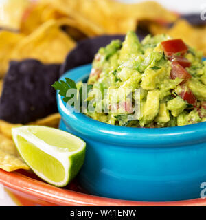 Un bol de guacamole frais avec des croustilles de maïs et un quartier de lime. Profondeur de champ intentionnel. Banque D'Images