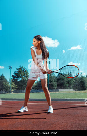 Slim et monter dark-haired woman holding racket formation sur cour Banque D'Images