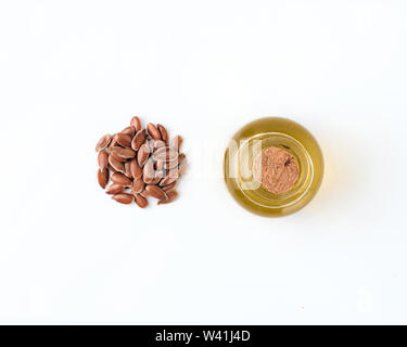 Les graines de lin et l'huile brute , isolé sur fond blanc. Tas de graines de lin et l'huile de lin brute dans de petites bouteilles de verre isolé sur blanc avec chemin, vue de dessus ou de télévision. Macro Banque D'Images