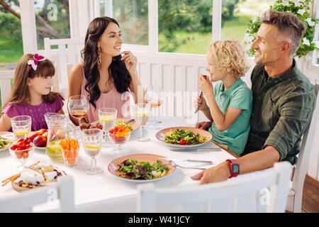 Les enfants et les parents de manger des salades délicieuses et parler Banque D'Images