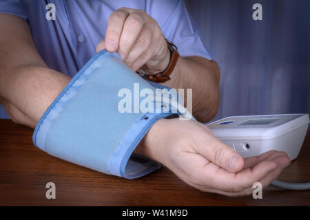 Un homme met un dispositif pour mesurer la pression artérielle Banque D'Images