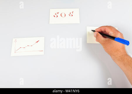 La main tient un stylo et écrit sur un autocollant. Banque D'Images