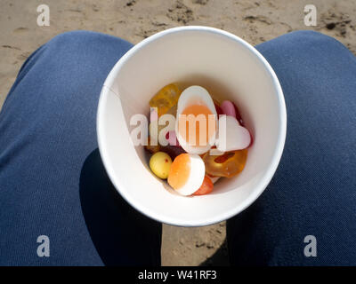 Pick n mix dans une tasse sur la plage Banque D'Images