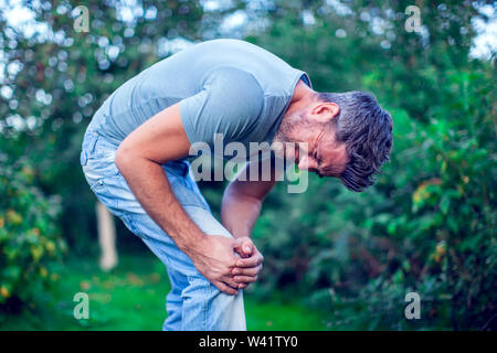 Les gens, les soins de santé et problème concept - close up d'un malheureux homme souffrant d'une douleur dans la jambe ou à l'extérieur du genou Banque D'Images