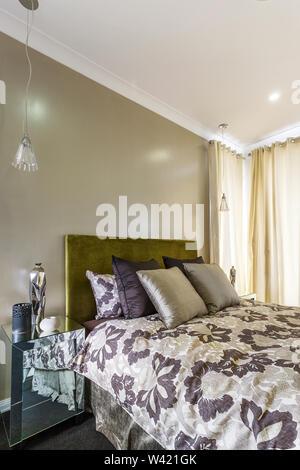 Chambre confortable dotée d'un double-lit avec coussins, une table avec des articles de décoration intérieure, luminaires suspendus et Banque D'Images