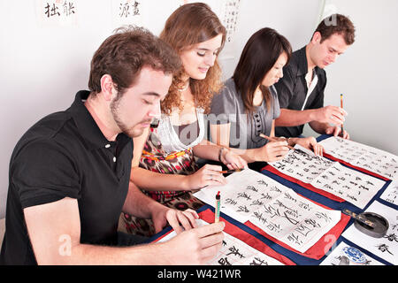 L'école ou du collège de jeunes filles et garçons d'écrire des lettres comme le chinois à l'aide de pinceaux et smiling Banque D'Images