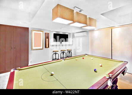 Table de billard moderne en chambre luxe avec meubles, trois lampes sont pendus au plafond, armoire en bois brun près de mur, les feux de l'équilibrage, l'accueil parfait dans Banque D'Images