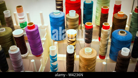 Les tiroirs de couleur close up sur une grille remplie de plusieurs tailles de filetage pour machine à coudre Banque D'Images