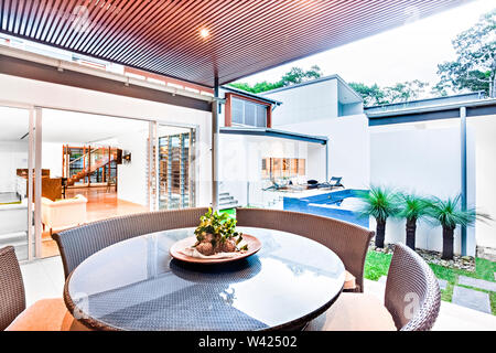 Table à manger moderne close up y compris table ronde en verre, la surface de l'usine de fantaisie avec la plaque à côté des chaises et l'entrée de porte à l'intérieur Banque D'Images