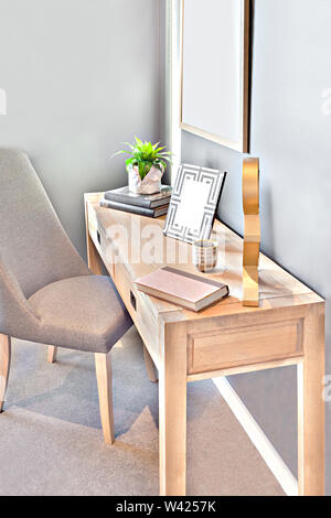 Petit espace de travail avec une chaise et table en bois dans une chambre moderne dont peu de livres avec un point fantaisie, la plante verte dans le vase blanc à proximité de soleil Banque D'Images