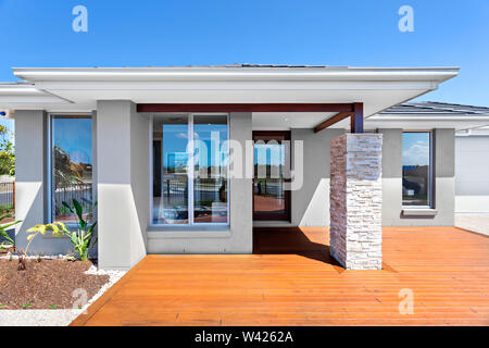 Avant d'une maison moderne avec jardin en bois. Le toit est supporté par des poutres apparentes avec des piliers en brique et pierre. La maison dispose d'au moins quatre fenêtres dans la vue Banque D'Images