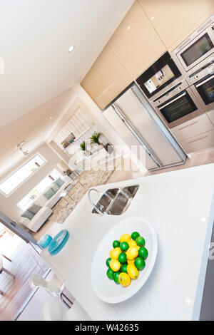 Cuisine de luxe dispose d'un grand réfrigérateur et four couleur argent fixée au mur, une plaque d'une épaisseur de blanc avec plein de fruits comme les citrons sur le col blanc Banque D'Images