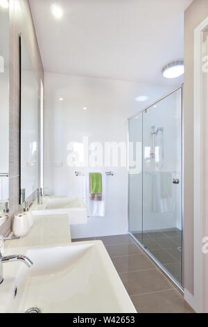 Salle de bain a une douche zone couvrant de panneaux de verre fixés sur les murs blancs. Le salon est éclairé par des lumières dans le lieu de baignade et Banque D'Images