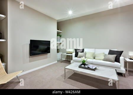 Cette chambre moderne dispose d''une télévision sur le mur près d'une chaise en bois, le sol a un tapis de laine. Une petite table blanche faite en céramique et en acier au milieu de la pièce, t Banque D'Images