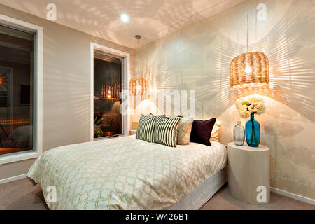 Oreillers sur le lit principal près de la table en forme de cylindre ou un tabouret. Il y a deux lampes suspendues sur le lit et se rapproche de la paroi. Le couvercle d'entre eux sont Banque D'Images