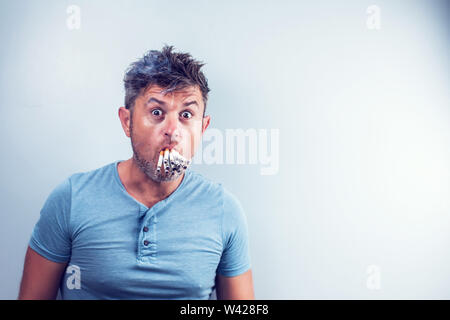 Jeune homme avec beaucoup de cigarettes dans sa bouche Banque D'Images