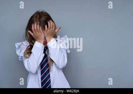 Petite lycéenne covering face, portrait de pleurer. Préadolescent a souligné, de peur d'essuyer l'enfant, cacher les larmes. Élève, étudiant à l'uniforme scolaire. Retour à l'école, triste, misérable petite fille prête pour la classe Banque D'Images