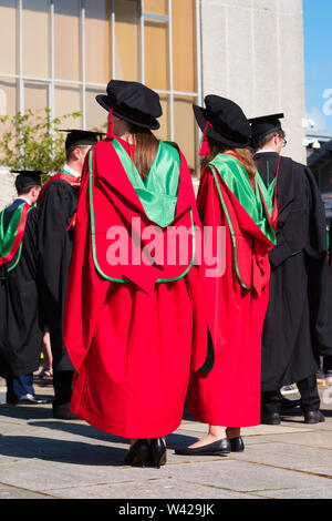L'enseignement supérieur au Royaume-Uni - deux étudiants de doctorat doctorat avec succès des femmes à la remise des diplômes à l'université d'Aberystwyth, après avoir reçu leur diplôme, portant leurs chapeaux bonnet de style Tudor traditionnel de couleur rouge et la toge. Juillet 2019 Banque D'Images