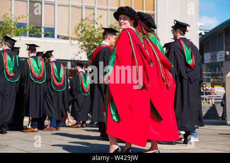 L'enseignement supérieur au Royaume-Uni - deux étudiants de doctorat doctorat avec succès des femmes à la remise des diplômes à l'université d'Aberystwyth, après avoir reçu leur diplôme, portant leurs chapeaux bonnet de style Tudor traditionnel de couleur rouge et la toge. Juillet 2019 Banque D'Images
