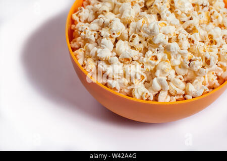 Une orange bowl with popcorn isolé sur fond blanc. Concept alimentaire Banque D'Images