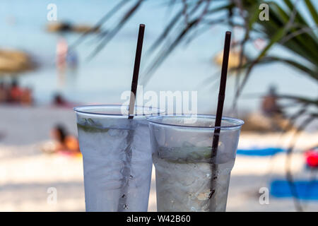 Deux cocktails glacés pailles avec happy hour au temps sur une plage tropicale Banque D'Images