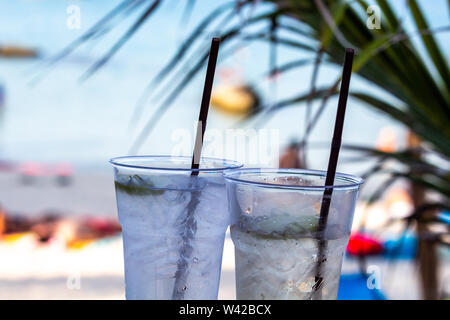 Deux cocktails glacés pailles avec happy hour au temps sur une plage tropicale Banque D'Images