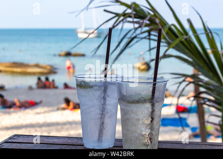 Deux cocktails glacés pailles avec happy hour au temps sur une plage tropicale Banque D'Images