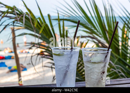 Deux cocktails glacés pailles avec happy hour au temps sur une plage tropicale Banque D'Images