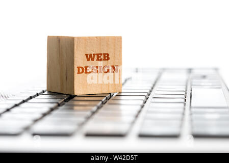 Web design, l'informatique et l'e-business concept avec une cale en bois debout sur un clavier d'ordinateur blanc avec les mots Web Design isolé sur blanc Banque D'Images