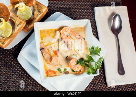 Soupe de crème de fruits de mer avec des toasts en plaque blanche sur la table. Banque D'Images