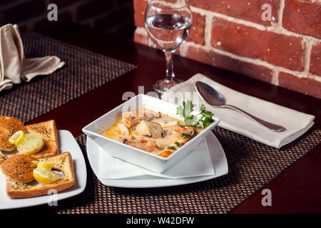 Soupe de crème de fruits de mer avec des toasts en plaque blanche sur la table. Banque D'Images